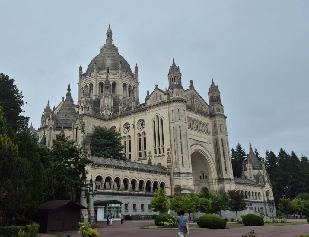 A low-angle view of the Basilica of Saint Thérèse of Lisieux in France, showcasing its massive central dome emphasizing the sheer architectural scale of the pilgrimage site.